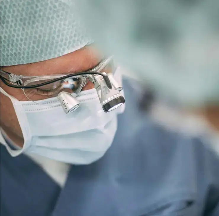 Zahnarzt in Bad Soden mit Vergrößerungsbrille und Mundschutz bei einer ästhetischen Zahnbehandlung – Fokus auf die detaillierte Arbeit und Präzision des Arztes.