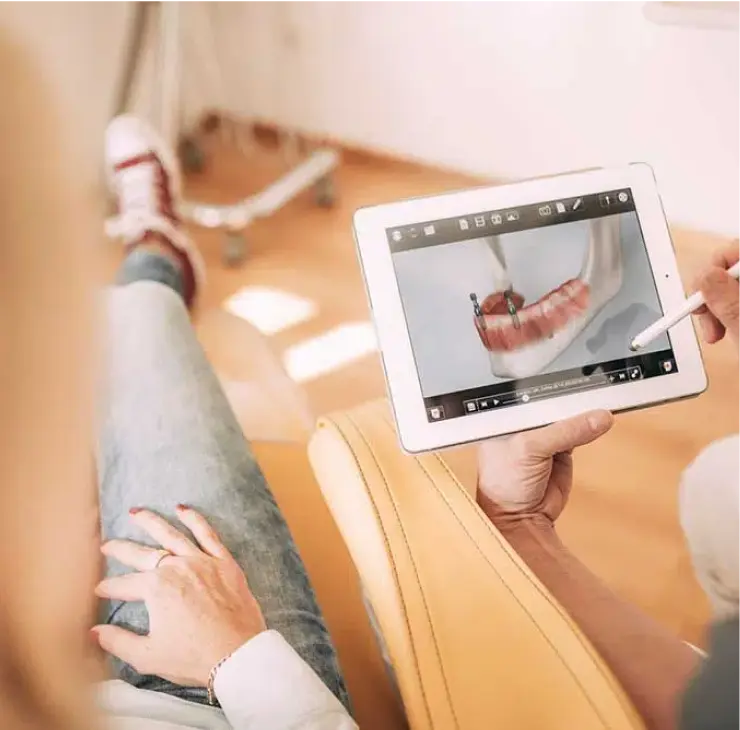 Patientin betrachtet den digitalen Ablauf einer Zahnimplantation auf einem Tablet in der Zahnarztpraxis Sandhofpassage Frankfurt.