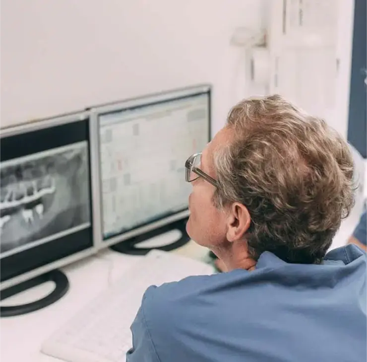 Zahnarzt überprüft Röntgenbild zur Beurteilung von Zahnimplantaten bei einem Patienten in der Zahnarztpraxis Sandhofpassage Bad Soden.